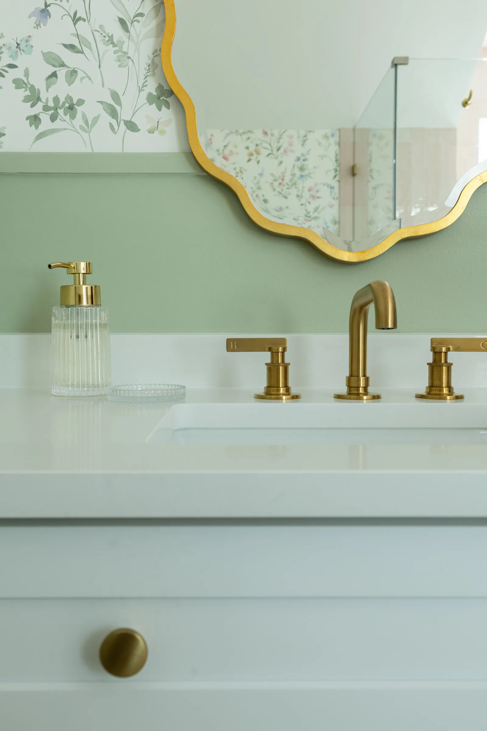 Close view of the brass tap and fluted glass soap dispenser on the powder room counter