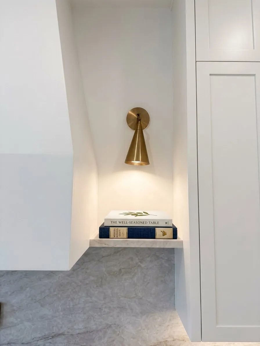 Brass wall light above a stone ledge set into the bathroom wall