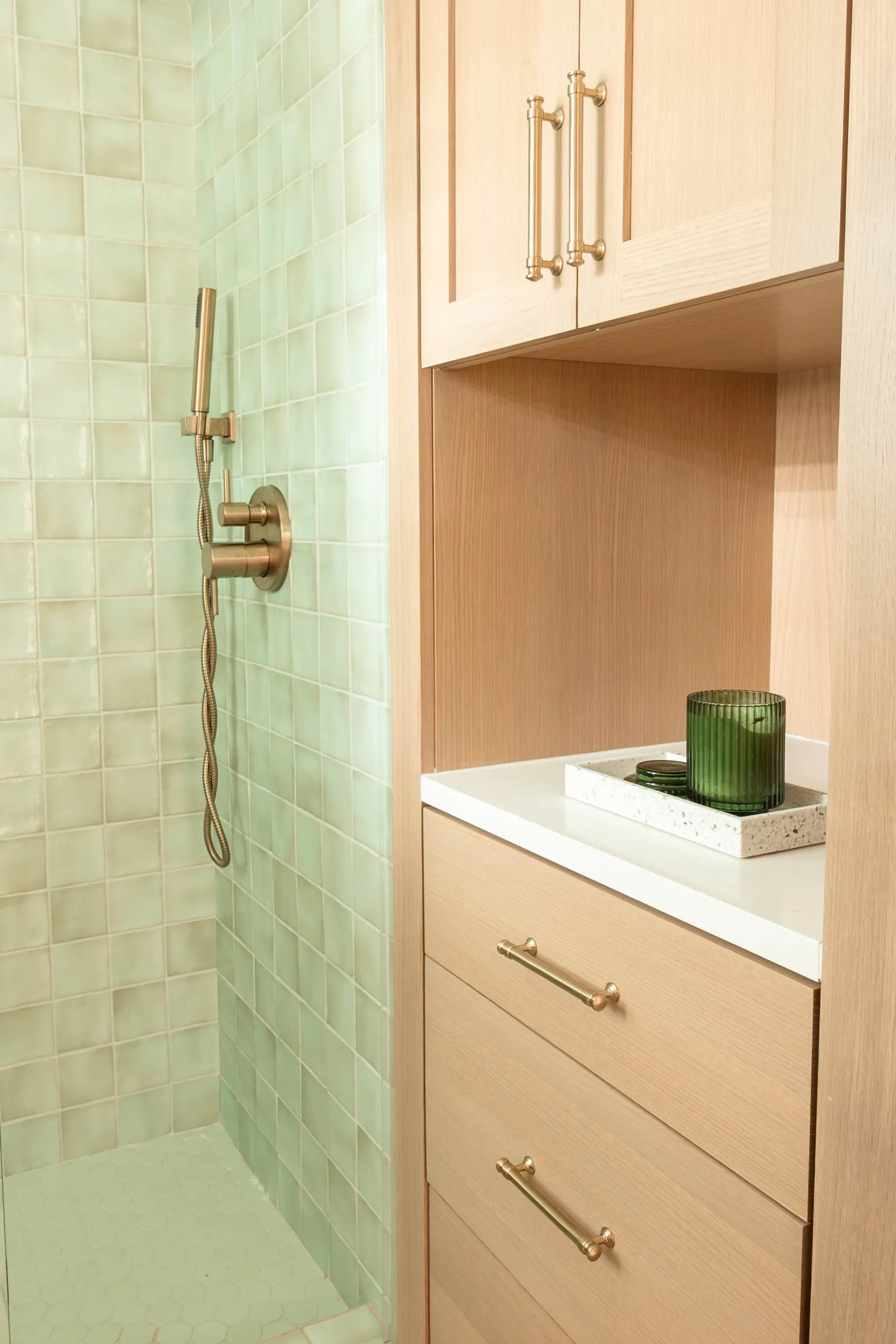 Detail of the brass shower valve against the uneven glaze of the green zellige tile