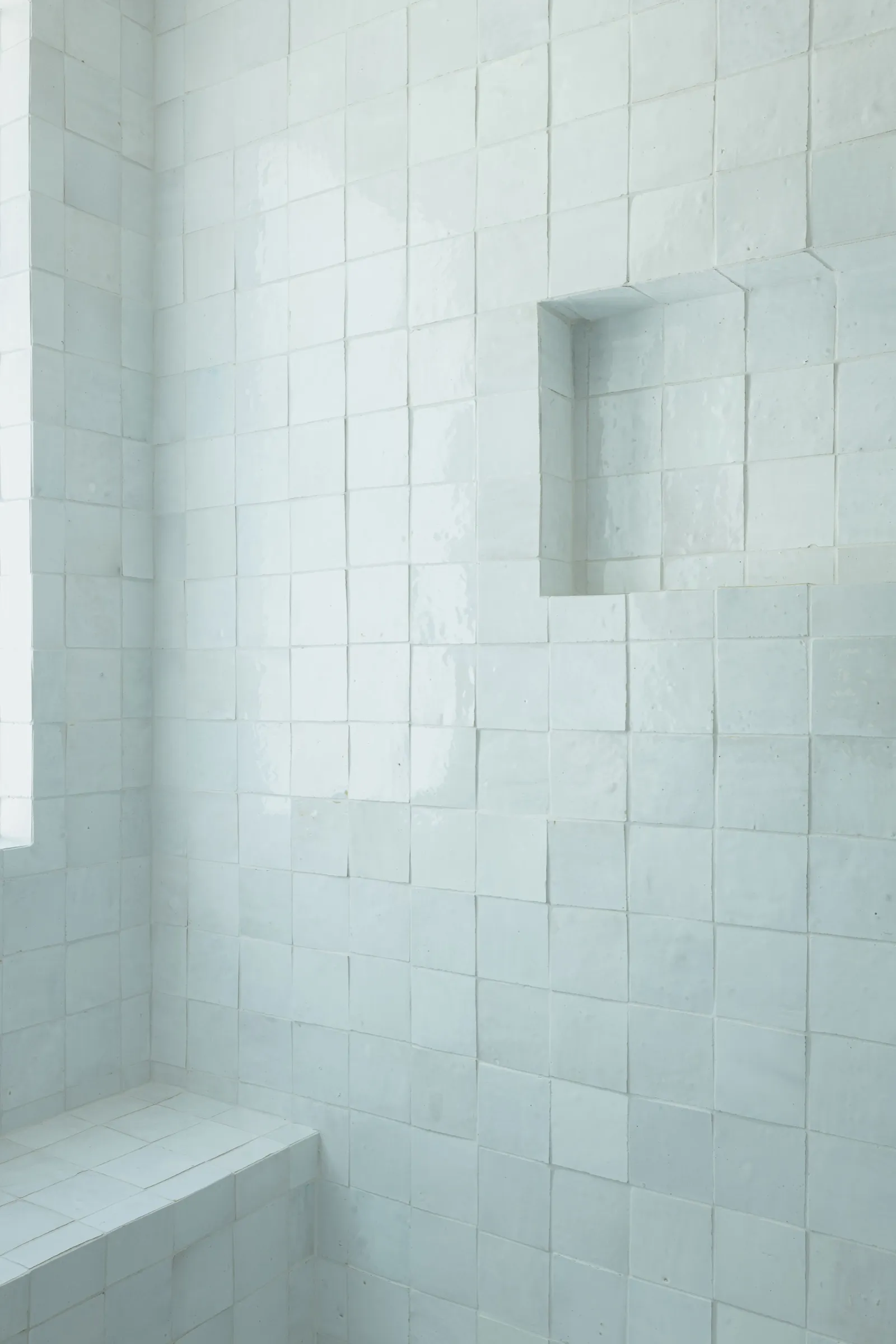 Close view of the uneven glaze on the white tile, with a niche and a built-in bench