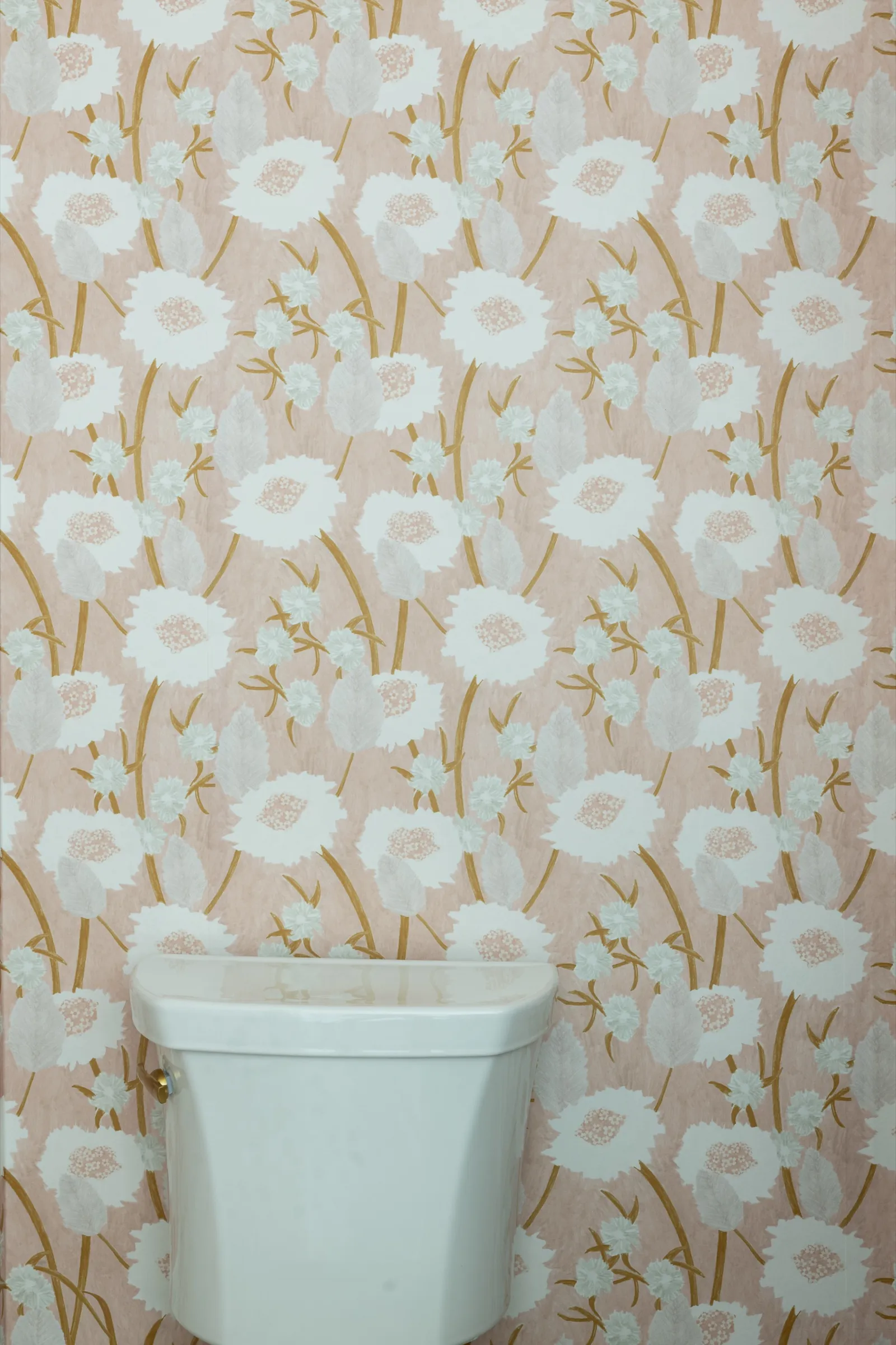 Blush poppy wallpaper carried across the wall behind the cistern